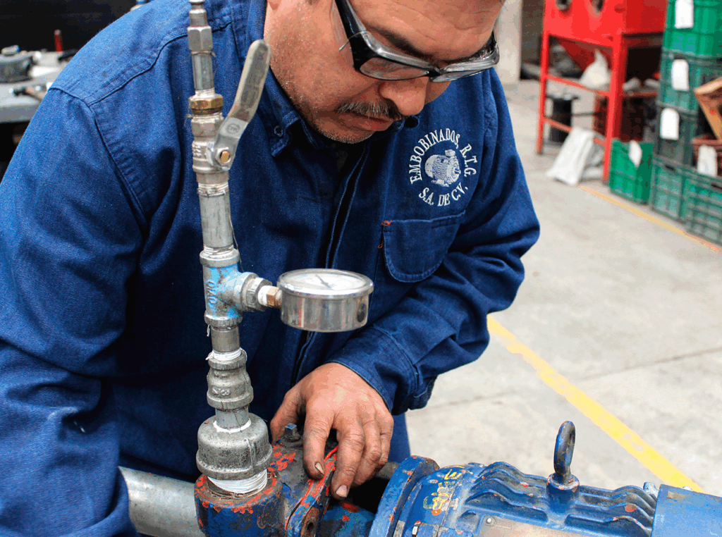 Técnico realizando prueba de presión en bomba industrial con manómetro y válvulas de control.