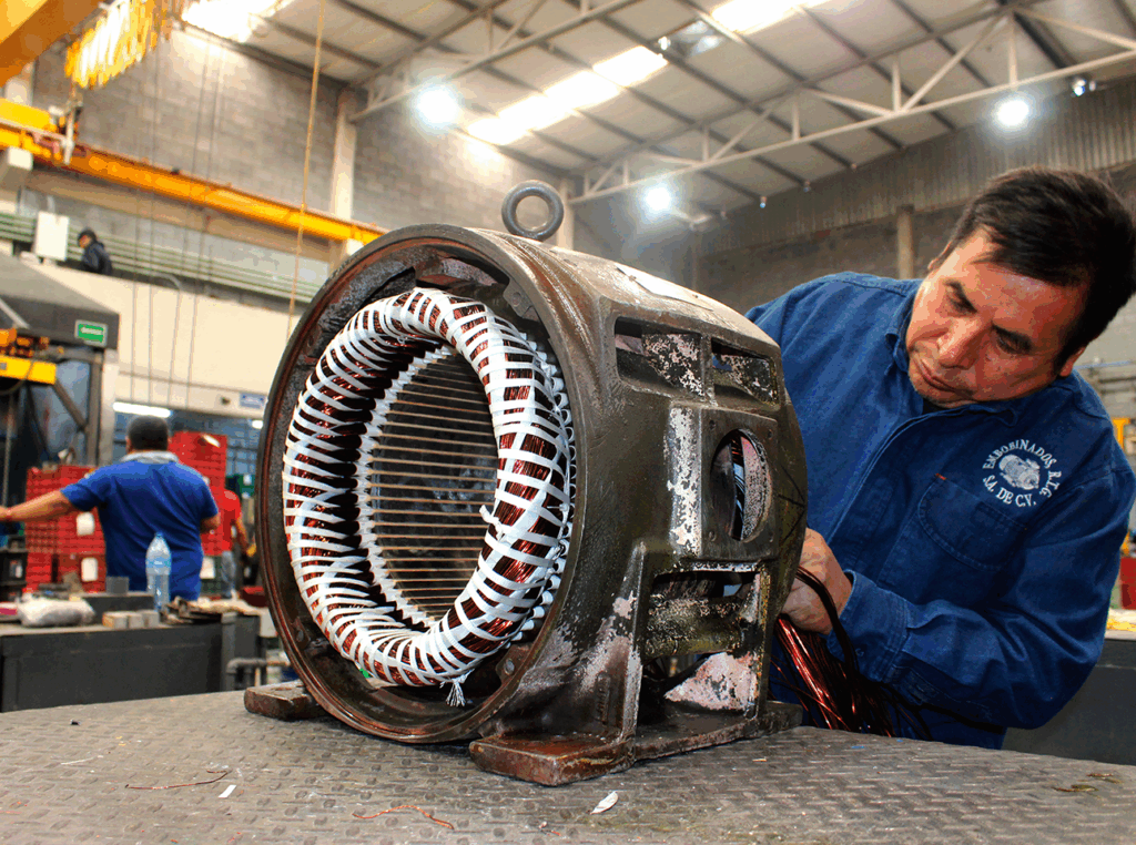 Técnico realizando rebobinado de motor eléctrico industrial en carcasa original durante mantenimiento correctivo.