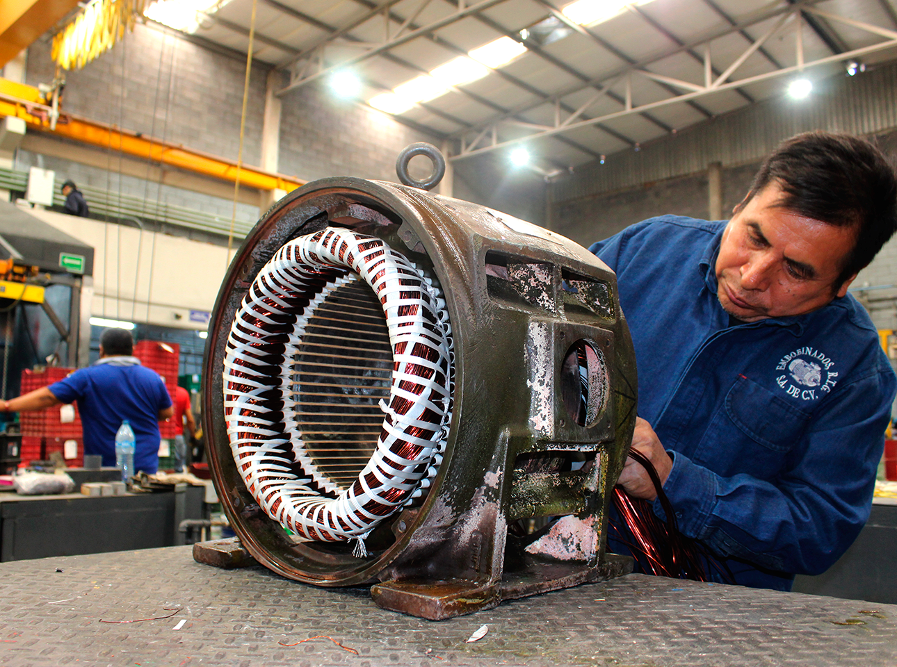 Técnico realizando rebobinado de motor eléctrico industrial en carcasa original durante mantenimiento correctivo.