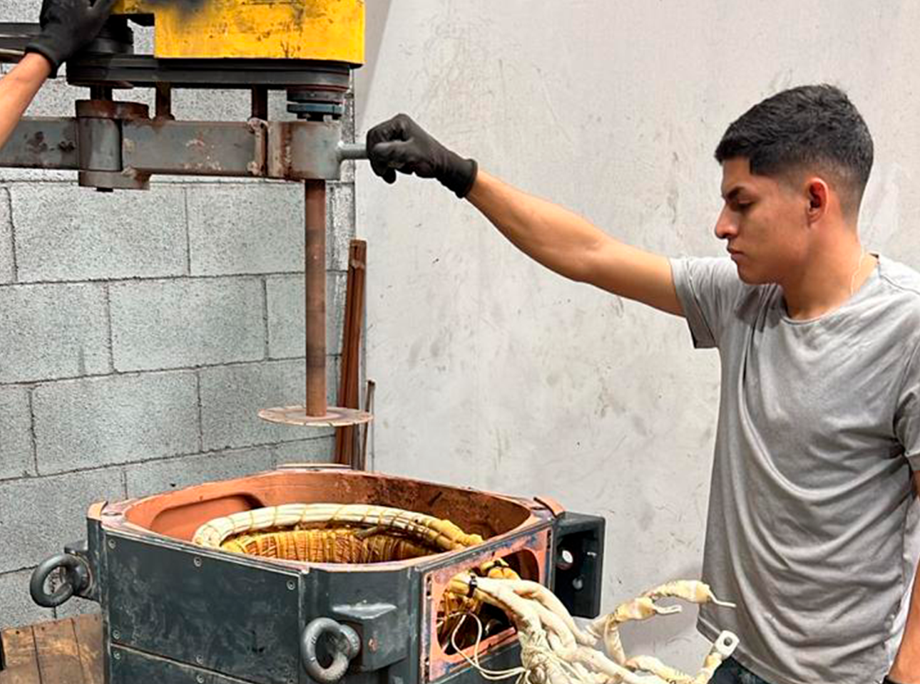 Técnico operando cortadora de coronas para retirar bobinas de un estator de motor eléctrico industrial.