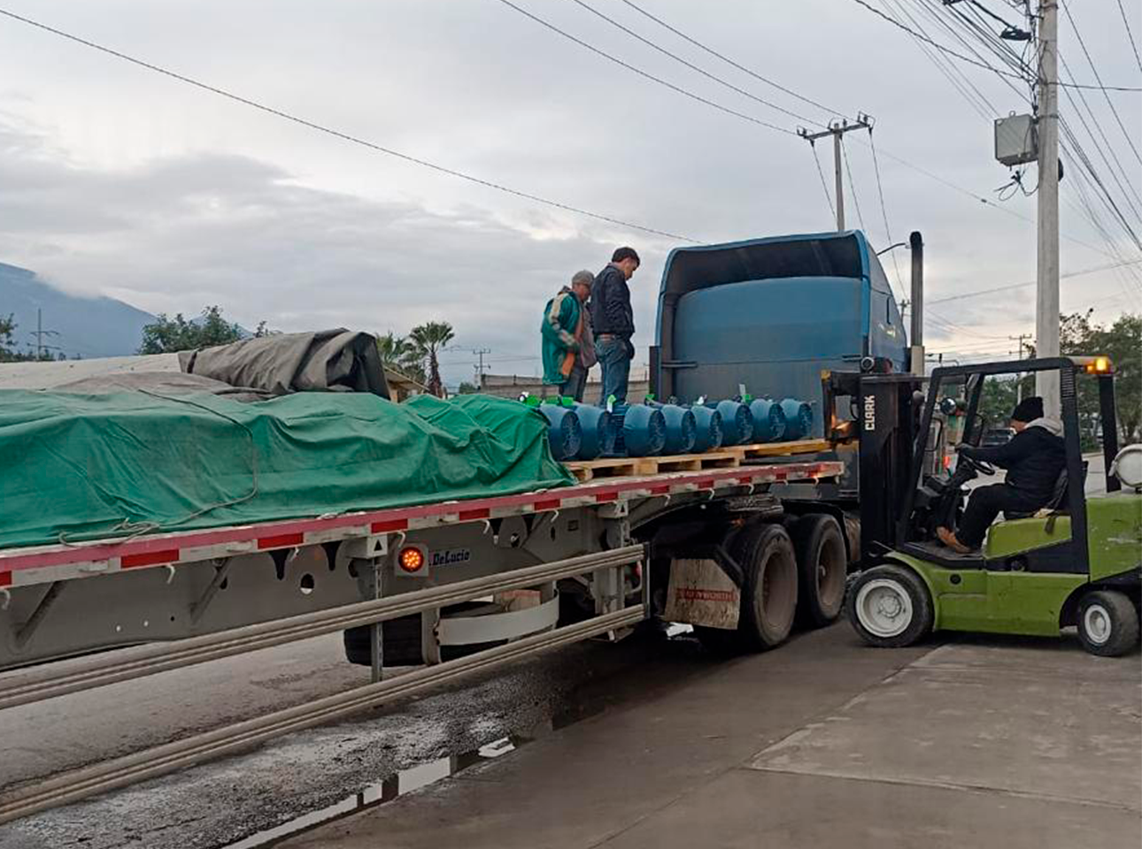 Descarga de motores eléctricos industriales con montacargas desde plataforma de tráiler en zona de recepción técnica.
