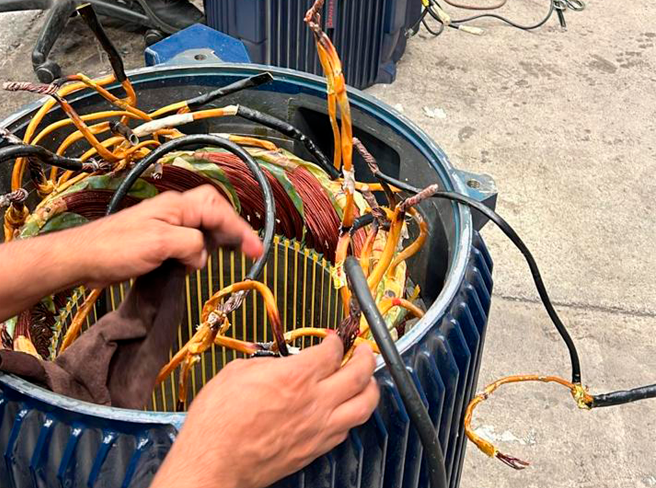 Técnico conectando cables de motor eléctrico industrial durante proceso de mantenimiento electromecánico.