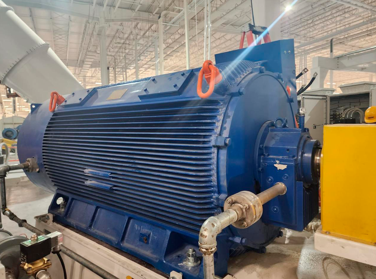 Motor eléctrico industrial de gran capacidad instalado en planta de producción, acoplado a sistema de transmisión.