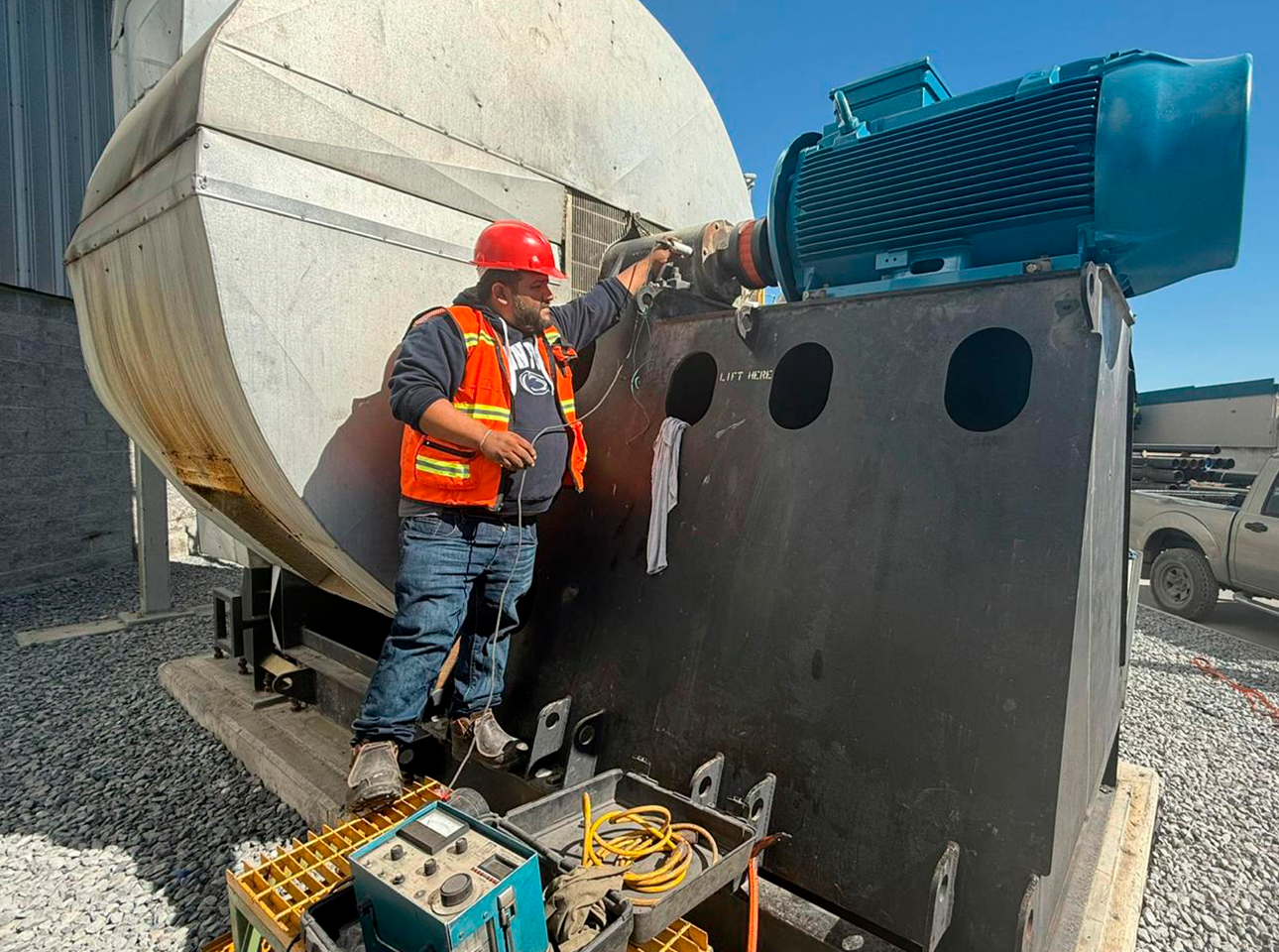 Técnico realizando balanceo dinámico en campo de ventilador industrial acoplado a motor eléctrico.
